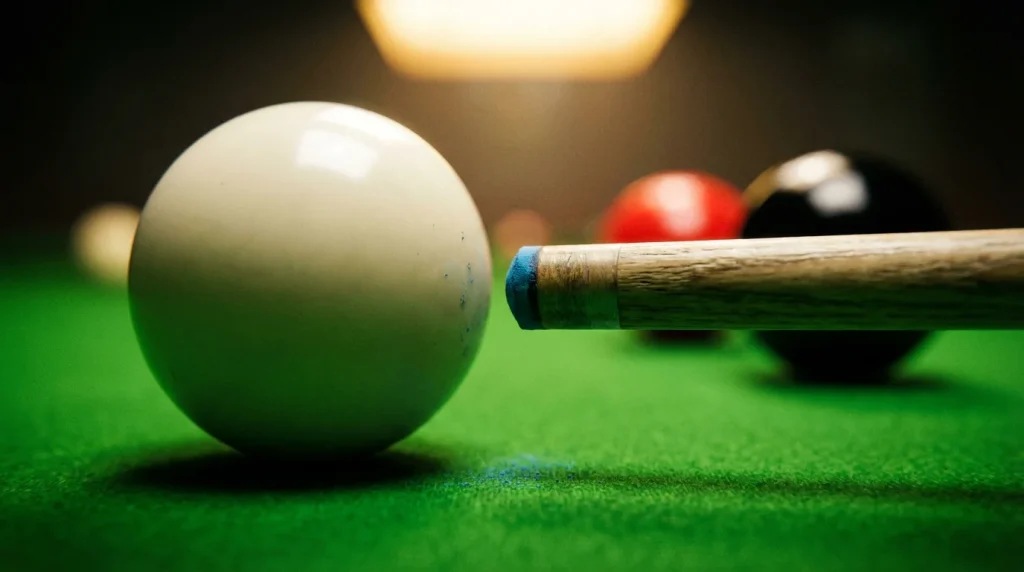 Gros plan sur une queue de snooker et la bille blanche sur le tapis vert